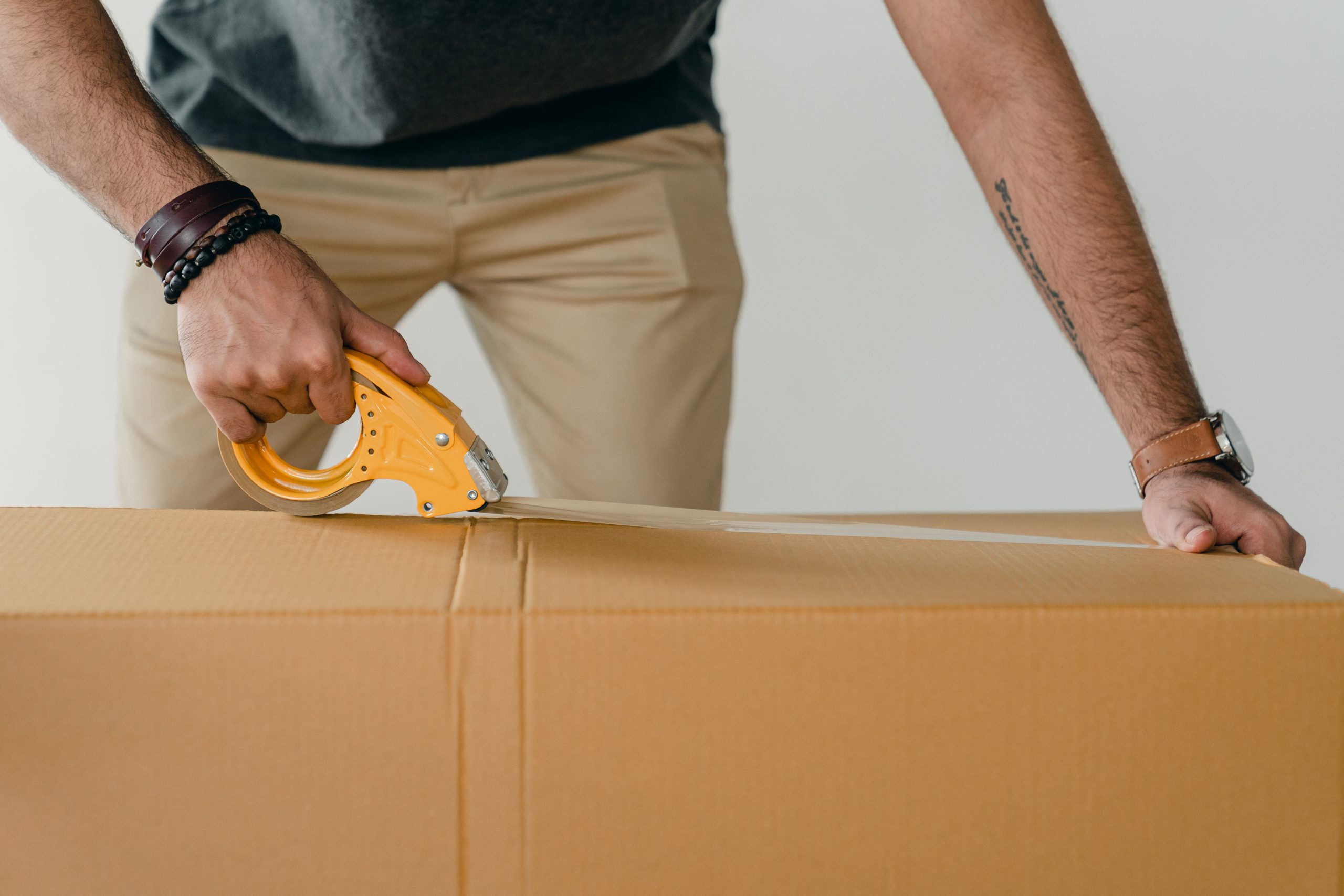 crop-man-sealing-carton-box-with-adhesive-tape-4246118